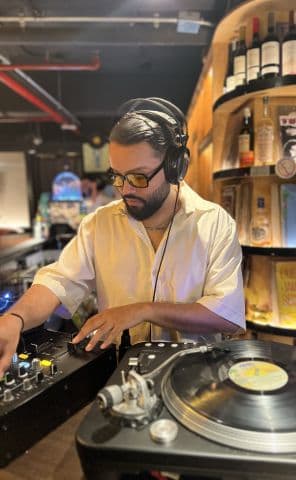 Frutamannn DJ Selector concentrado tocando vinilo en set íntimo en bar de Barranquilla