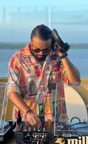 Frutamannn DJ Selector tocando en vinilo con camisa tropical al atardecer en exterior